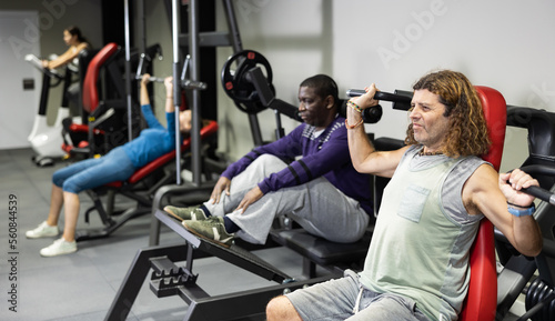 Fototapeta Naklejka Na Ścianę i Meble -  Caucasian man training on shoulder press machine in gym