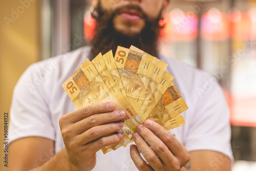 Um homem segurando notas do Real Brasileiro. Notas de 50 Reais. Leque de dinheiro. Economia brasileira e negócios. photo