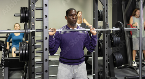 African american man doing barbell squats in the gym