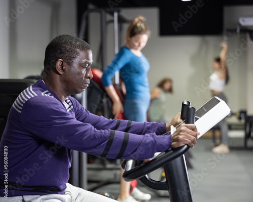 African-american man training on exercise bike in gym