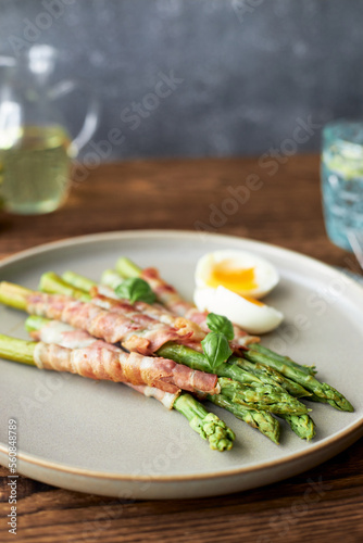 Fresh asparagus wrapped in bacon and grilled, served with egg benedict. Healthy food.