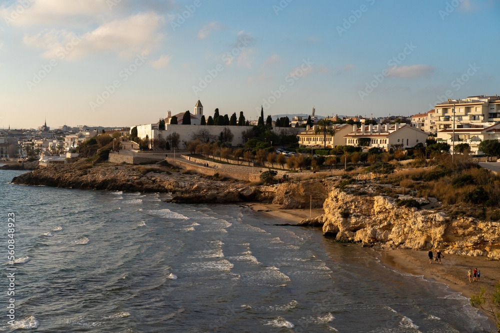 Rocky sea coast of the city of Sitges during the sunset. Cozy and calm Spanish city nearby the Mediterranean sea.