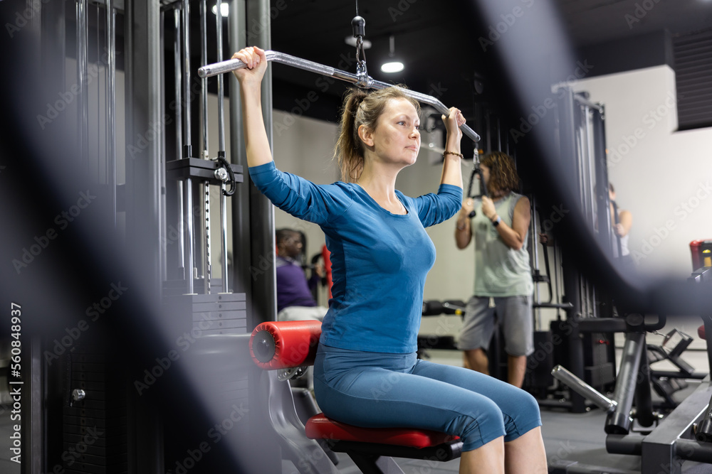 Athletic young woman works out on simulator in gym