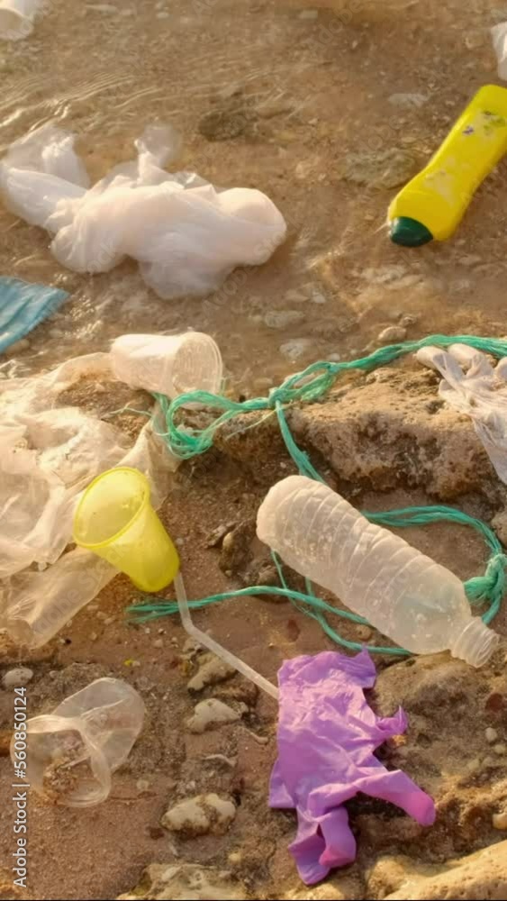 VERTICAL VIDEO, Close-up of disposable plastic and other debris on corals beach in surf zone. Plastic and other garbage on the seashore. Slow motion VERTICAL VIDEO, Close-up of disposable plastic and other debris on corals beach in surf zone. Plastic and other garbage on the seashore. Slow motion