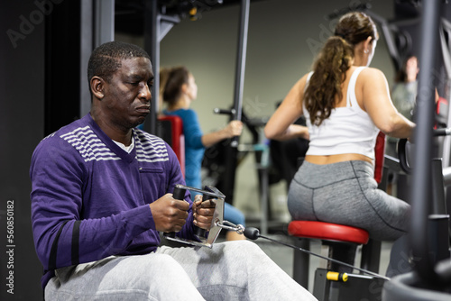 African-american man training on cable row machine in gym