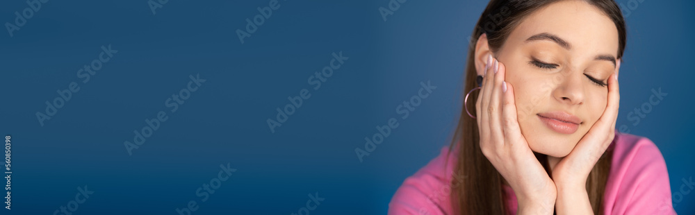 Pretty teenage girl touching face isolated on blue, banner. Pretty teenage girl touching face isolated on blue, banner.