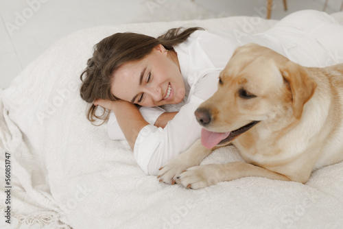 girl in white clothes with dog labrador playing at home