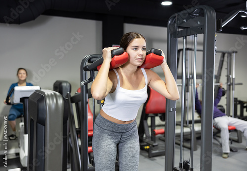 Young woman is engaged on simulator to strengthen muscles of legs in the gym
