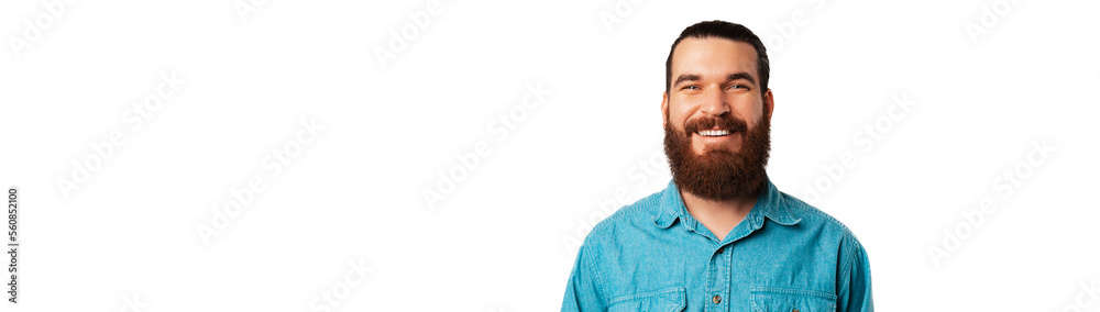 Obraz premium Banner shot of a wide smiling young bearded man wearing blue jeans shirt.