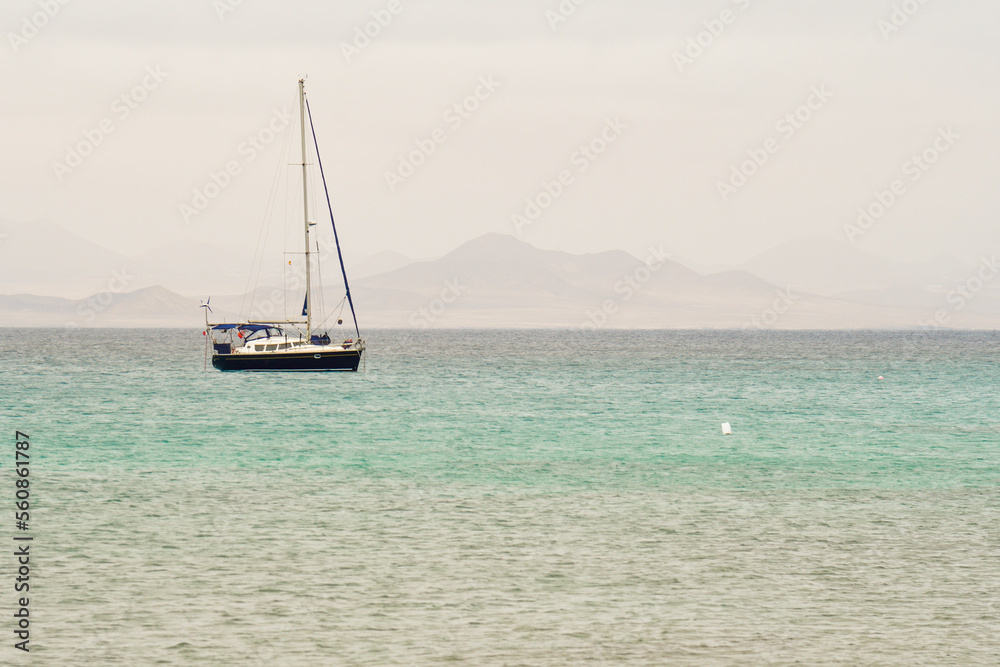 Fototapeta Sailboat with the volcanoes of Caleta de Famara in the background