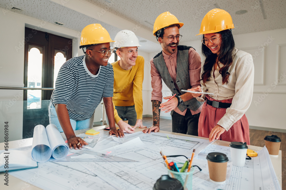 Multiracial team of architects having a meeting while using blueprints Multiracial team of architects having a meeting while using blueprints
