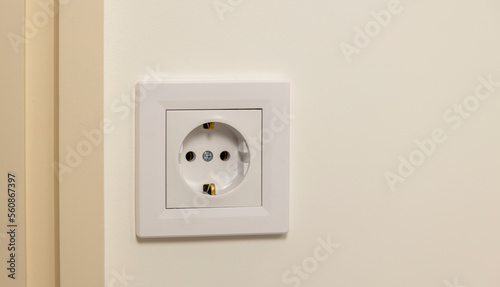 Electricity supply. Electric socket isolated on white wall. Renovated studio apartment, power background. Place for text. Focus on the outlet.