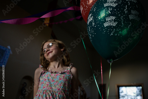 A young girl smiles while standing next to balloons during a birthday party celebrating her eighth birthday, in Breckenridge, Co