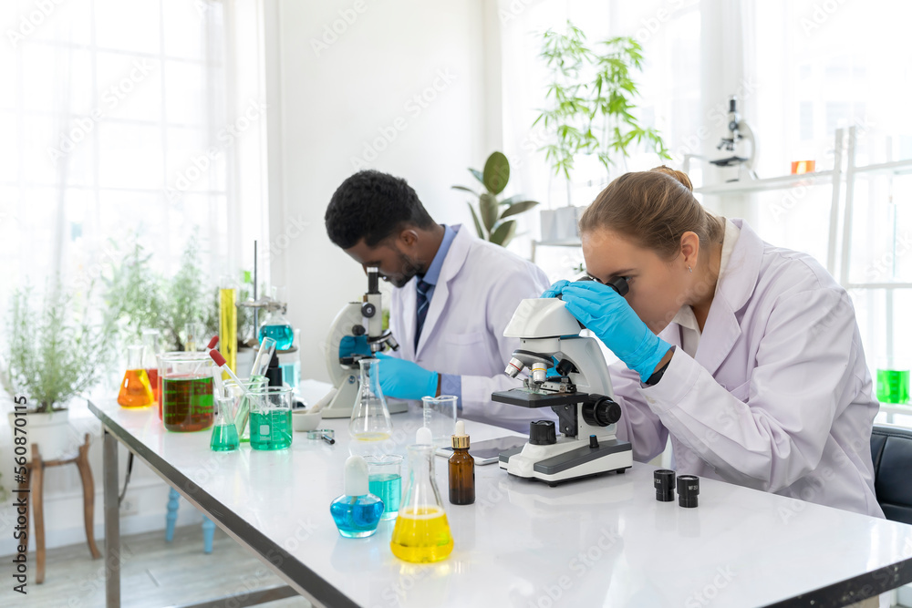 Young female scientist working with microscope in laboratory Young female scientist working with microscope in laboratory