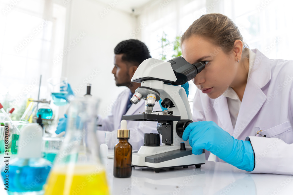 Young female scientist working with microscope in laboratory Young female scientist working with microscope in laboratory