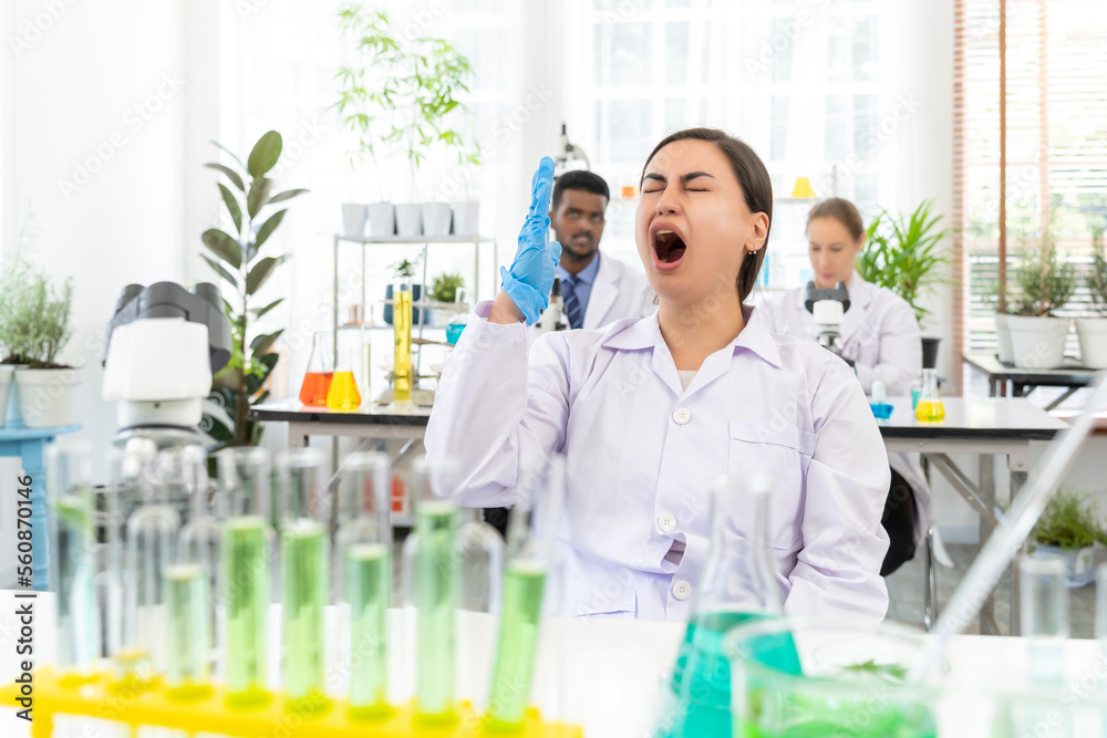 Young scientist female is yawning while working in laboratory Young scientist female is yawning while working in laboratory