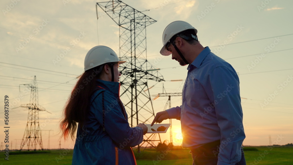 Two construction engineers work together on an electrical transmission