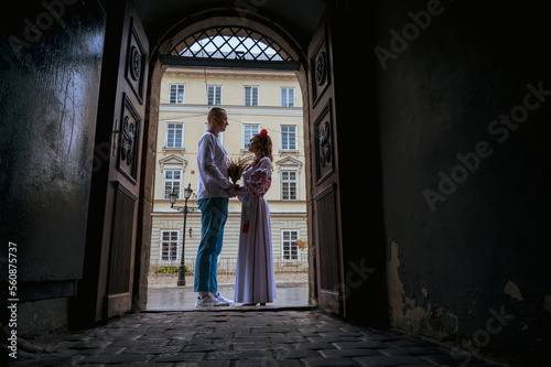 Emotional portrait of a happy young couple in love, a family hugging, holding hands in the city of Lviv in traditional Ukrainian shirts, holding hands. Young people hug in the old town of Lviv