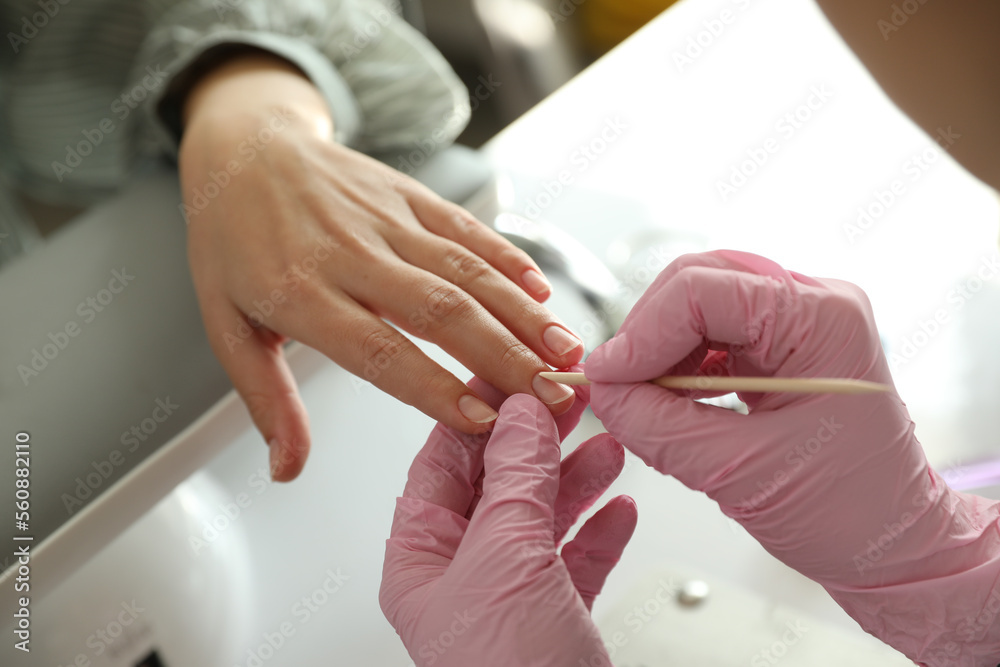 Professional manicurist working with client in beauty salon, closeup