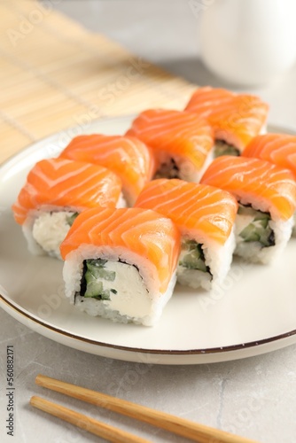 Tasty sushi rolls and chopsticks on grey table, closeup