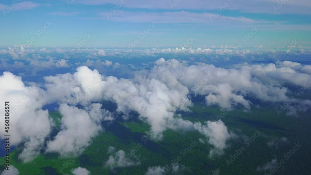 A beautiful scene of clouds and a forested coast as seen from the window of a plane in daylight. A beautiful scene of clouds and a forested coast as seen from the window of a plane in daylight.