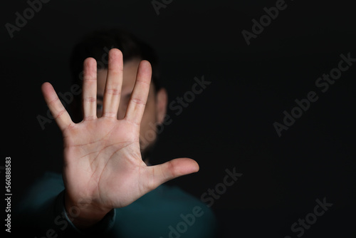 Man showing stop gesture against black background, focus on hand. Space for text