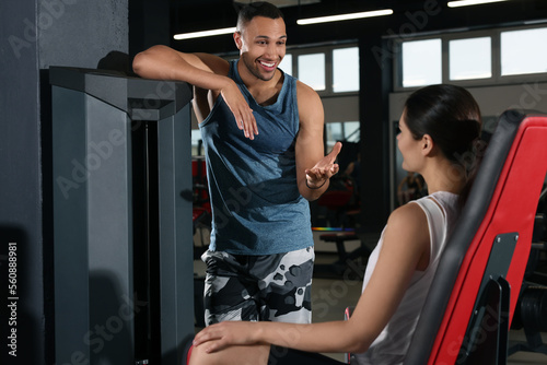 Happy trainer having discussion with woman in gym