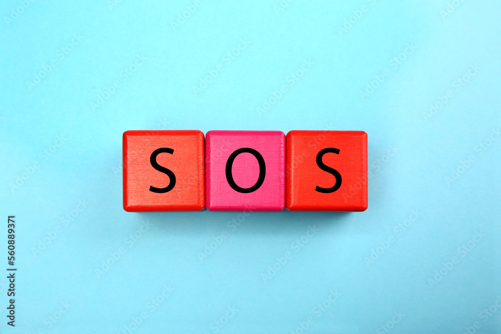Abbreviation SOS (Save Our Souls) made of color cubes with letters on light blue background, top view Abbreviation SOS (Save Our Souls) made of color cubes with letters on light blue background, top view
