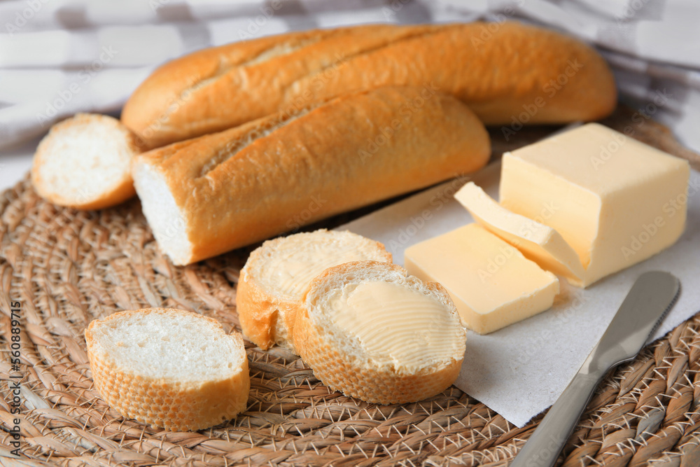 Tasty cut baguette with fresh butter on wicker mat Tasty cut baguette with fresh butter on wicker mat