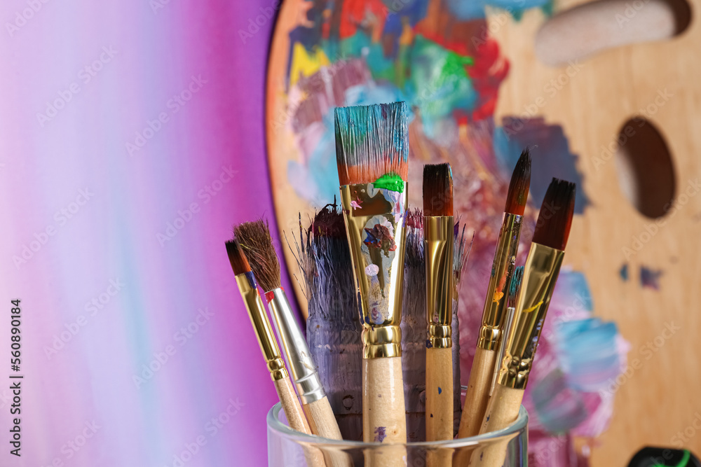 Fototapeta premium Brushes with colorful paints and wooden artist's palette. Space for text