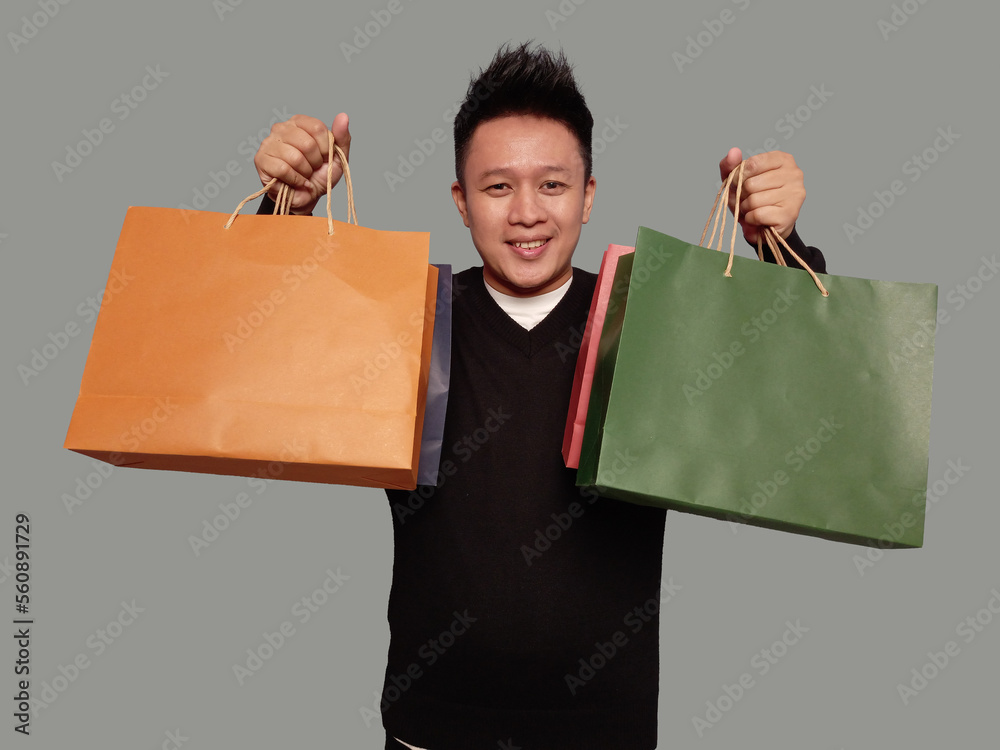 Casual man holding shopping bags in both hands with smile facial expression Casual man holding shopping bags in both hands with smile facial expression
