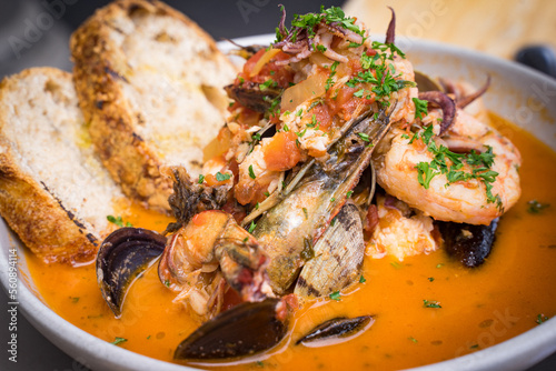 Stew with seafood from Italy. Clams, mussels, squids, and shrimp are cooked in a tomato sauce with cheeses and herbs. To increase the savory, Calabrian chilis are added. Dip with bread. photo
