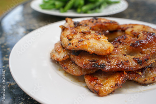 Pork belly is fried with oil. Before that it is well marinated with fish sauce, sugar, black pepper, chopped garlic. After frying for more than 10 minutes, serve with plain rice and boiled vegetables.