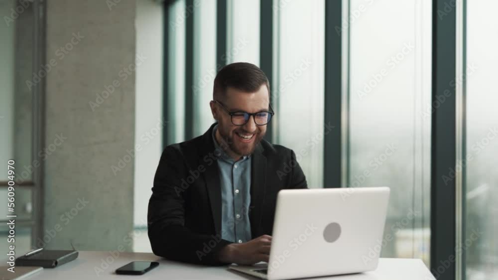 A cheerful man sitting at a laptop begins to laugh at what he saw A cheerful man sitting at a laptop begins to laugh at what he saw