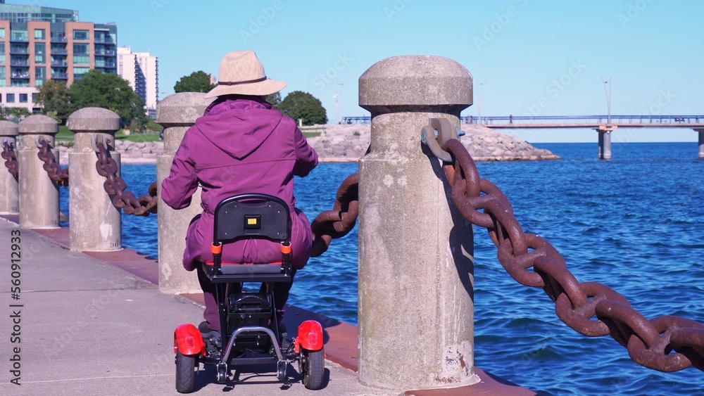 Woman with disability in the wheelchair mobility scooter enjoying park