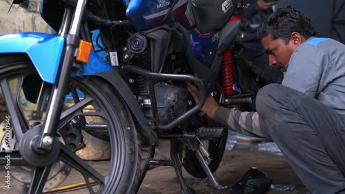 Young man repairing or preparing a motorbike for a new season after winter time, basic motorcycle maintenance