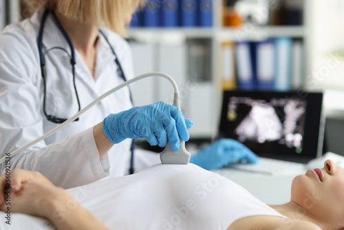 Doctor makes breast ultrasound to young woman in clinic closeup