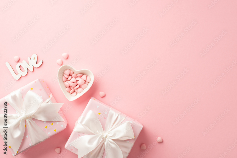 Valentine's Day concept. Top view photo of present boxes with white ribbon bows heart shaped saucer with sprinkles and inscription love on isolated pastel pink background with copyspace Valentine's Day concept. Top view photo of present boxes with white ribbon bows heart shaped saucer with sprinkles and inscription love on isolated pastel pink background with copyspace