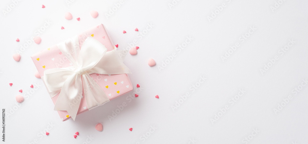 Valentine's Day concept. Top view photo of pastel pink giftbox with silk ribbon bow and heart shaped sprinkles on isolated white background with empty space Valentine's Day concept. Top view photo of pastel pink giftbox with silk ribbon bow and heart shaped sprinkles on isolated white background with empty space