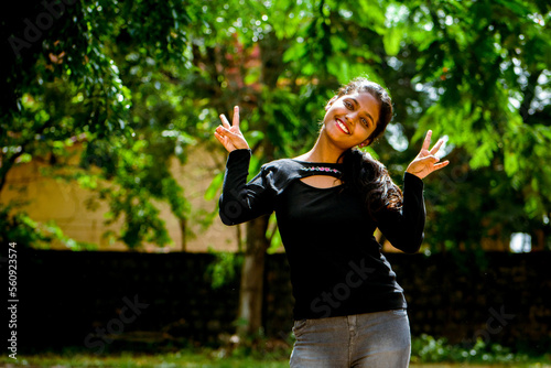 Attractive carefree dark women showing peace gesture ,with both hands in the park.