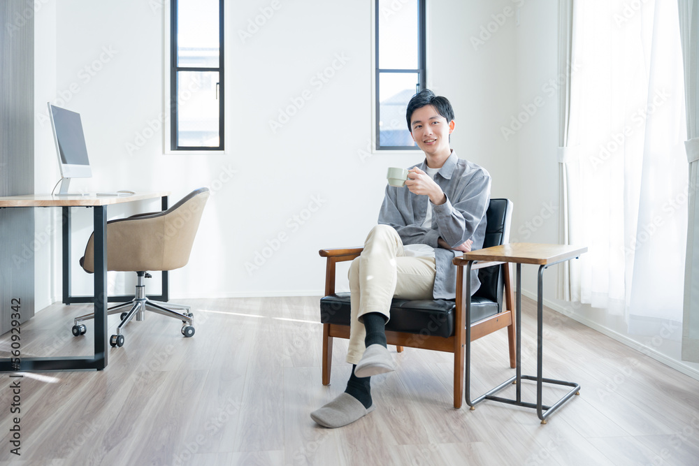 家でコーヒーを飲んでリラックスする若い男性 家でコーヒーを飲んでリラックスする若い男性