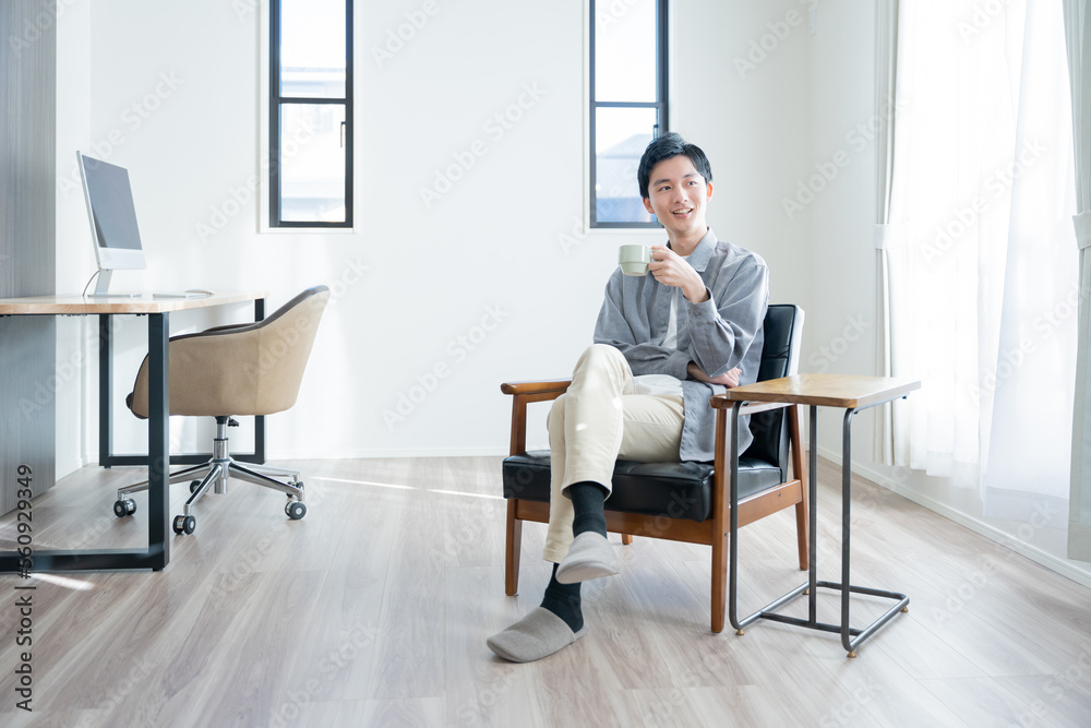 家でコーヒーを飲んでリラックスする若い男性 家でコーヒーを飲んでリラックスする若い男性