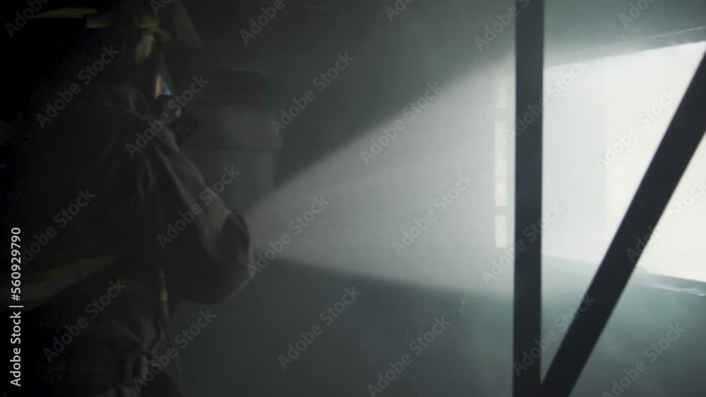 Water spraying from hose out window clears smoke from burning building. Firefighter uses ventilates room using hydraulic ventilation technique. Fireman training. Water spraying from hose out window clears smoke from burning building. Firefighter uses ventilates room using hydraulic ventilation technique. Fireman training.