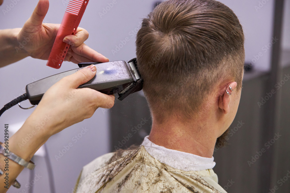Fototapeta premium hairdresser cuts hair with a machine clipper. Haircut service. Man hairstyle