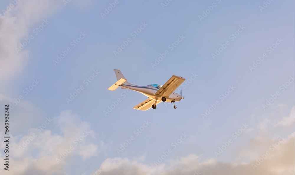 Obraz premium A light plane flying through the clouds at sunset