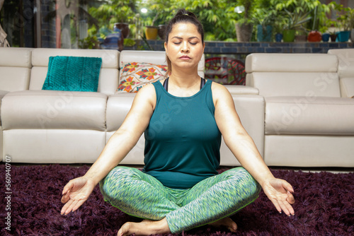 Young indian woman in sportswear doing siddhasana yoga meditation pose at at home. Full length shot. photo