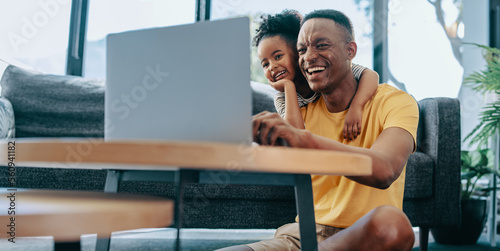 Dad and daughter watch an interesting video on a kids channel online. Happy father in his 30s spending leisure time with his daughter at home