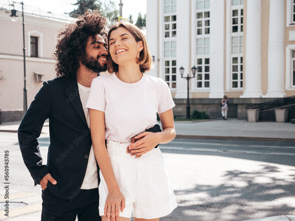 Fototapeta premium Smiling beautiful woman and her handsome boyfriend. Sexy cheerful multiracial family having tender moments in the street at sunset. Multiethnic models hugging. Embracing each other. Love concept