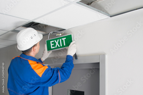 Canvastavla a master in uniform, servicing emergency evacuation exits, repairs the warning s
