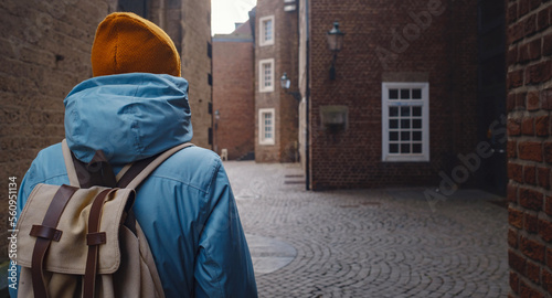 winter travel to Dusseldorf, Germany. young Asian tourist in blue jacket and yellow hat (symbol of Ukraine) walks through sights of old town or Altstadt. Popular center of Rheinland and Westphalia © YURII Seleznov